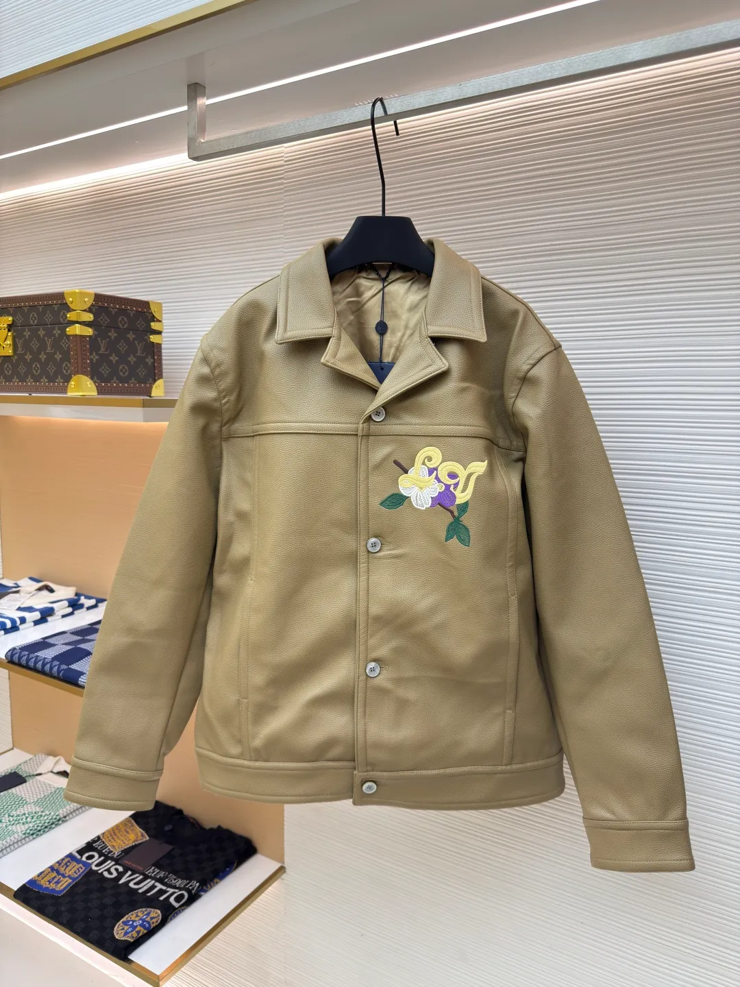 LOUIS VUITTON Tunic Jacket ●Authentic product: Purchased and developed by 50050 ●Item number: 1680165-C00 ●Fabric: Leather fabric ●Technology: Positioning cutting machine ●Version: Fitted version ●Weight: about 1365 grams ●Size: 50-52-54-56 ●Description: 24ss new tunic jacket has the retro connotation of gorgeous grain leather, with LV Flower Embroidery interprets seasonal tropical island elements. Marque L. Vuitton déposée leather patch sits at the back, and pearlescent buttons add a chic touch. The overall workmanship is very complicated. The embroidery is made with heat-capacitive glue, which needs to be ironed to ensure quality. The checkerboard pattern needs to be positioned correctly, so it is very fast. Each process of the entire garment is slow and time-consuming.